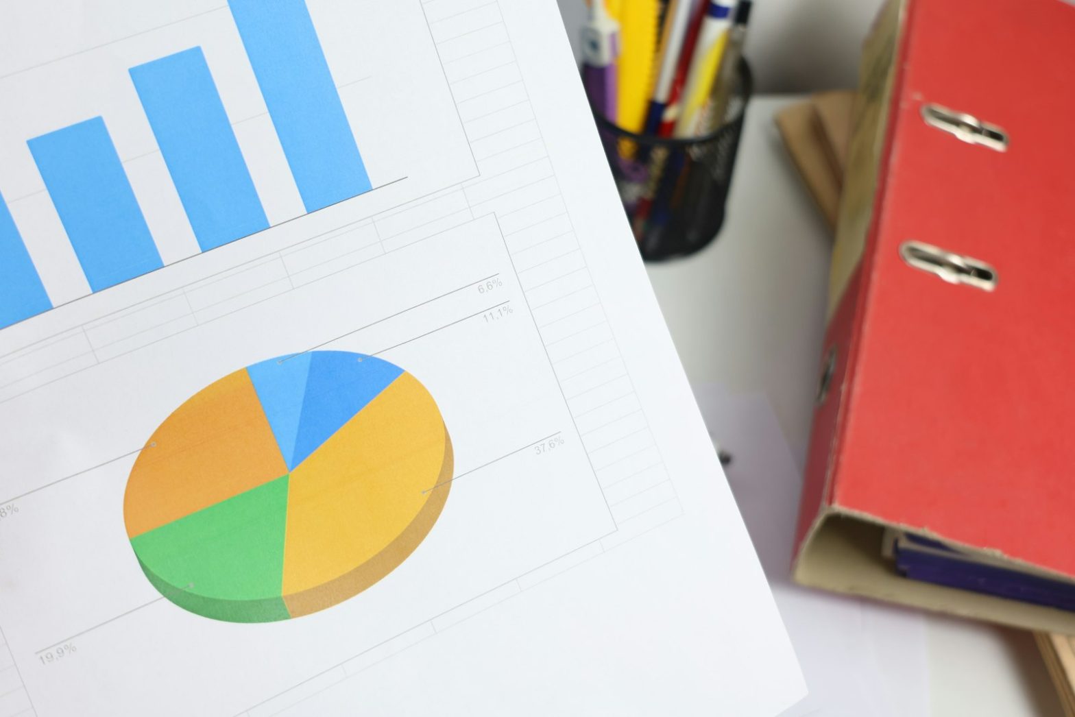Printed bar and pie charts beside folders on a desk
