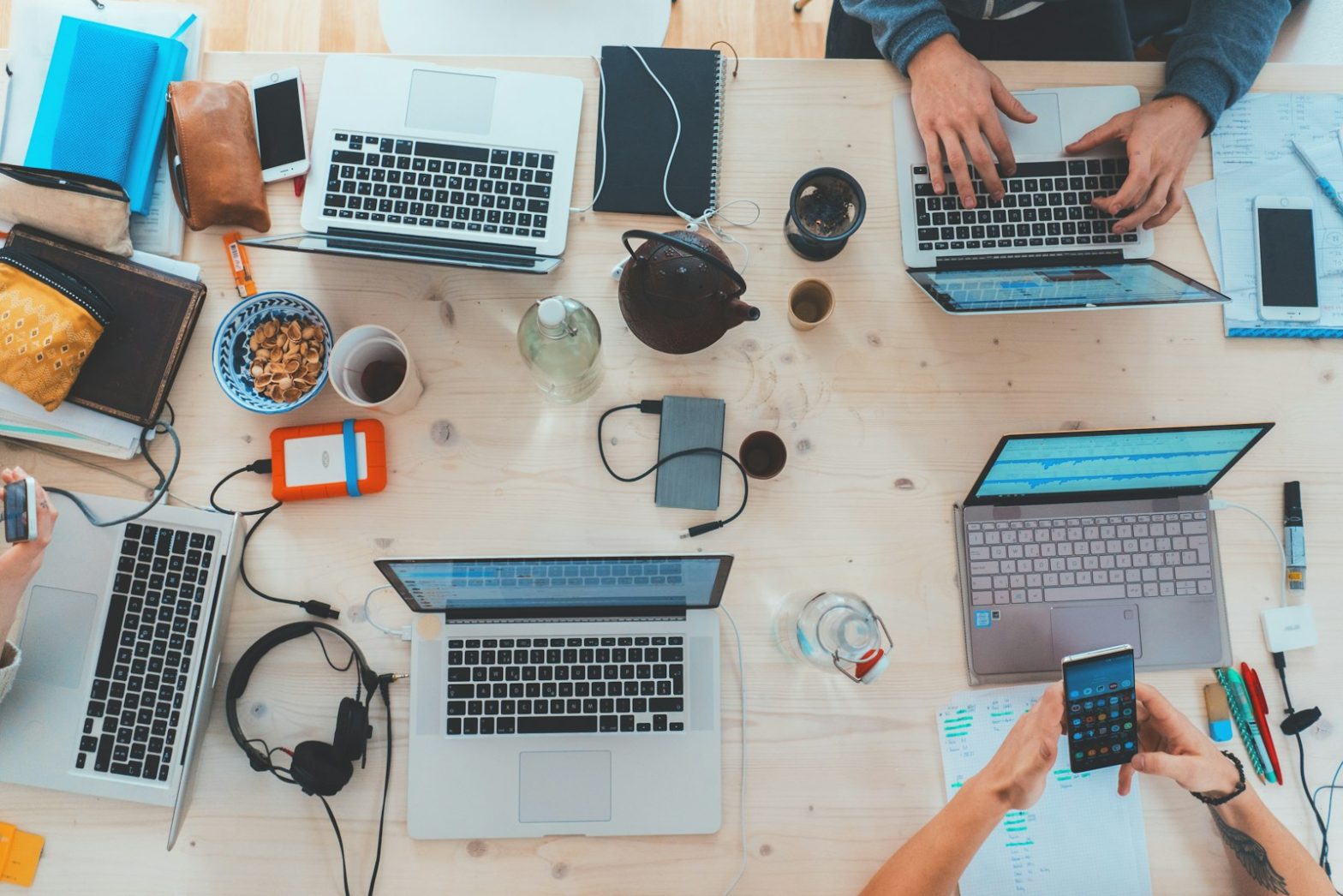 A team working on laptops around a shared table, seen from above